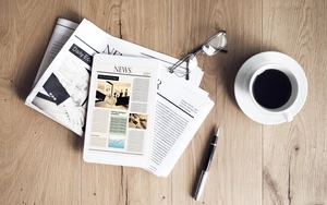 Newspaper with tablet on wooden table