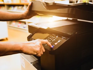 Close-up of a hand pressing the copy button on an office photocopier