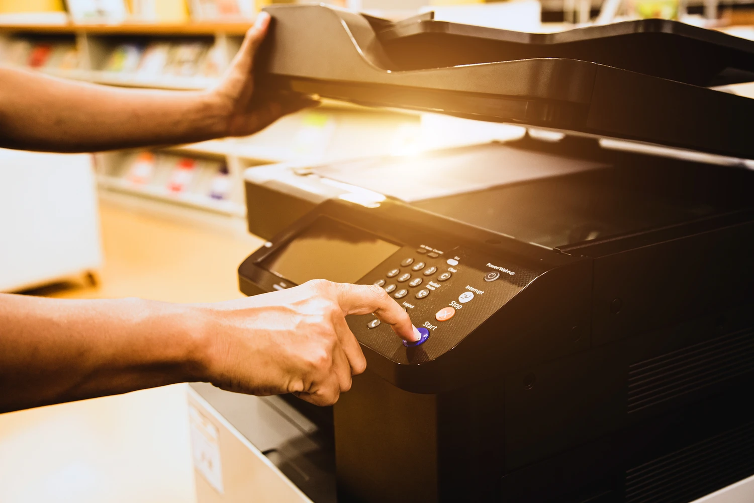 Close-up of a hand pressing the copy button on an office photocopier